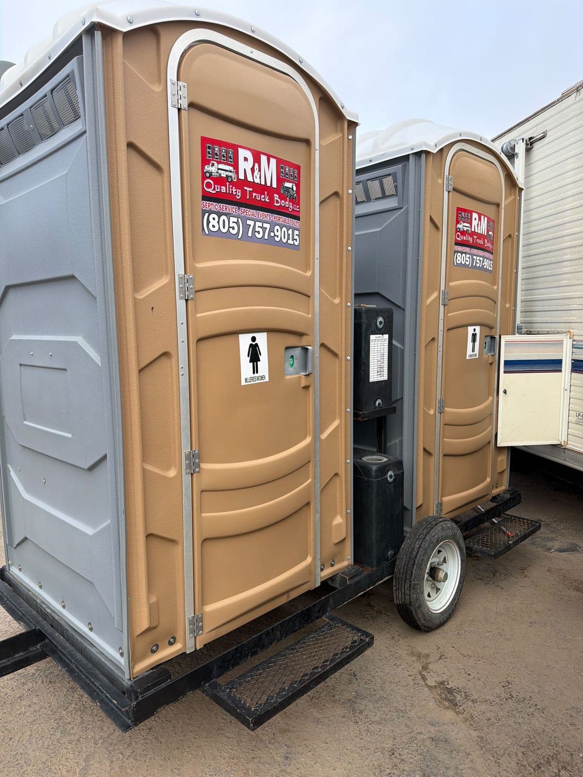 Portable restroom mounted on a field sanitation trailer, with a women's sign and step platform