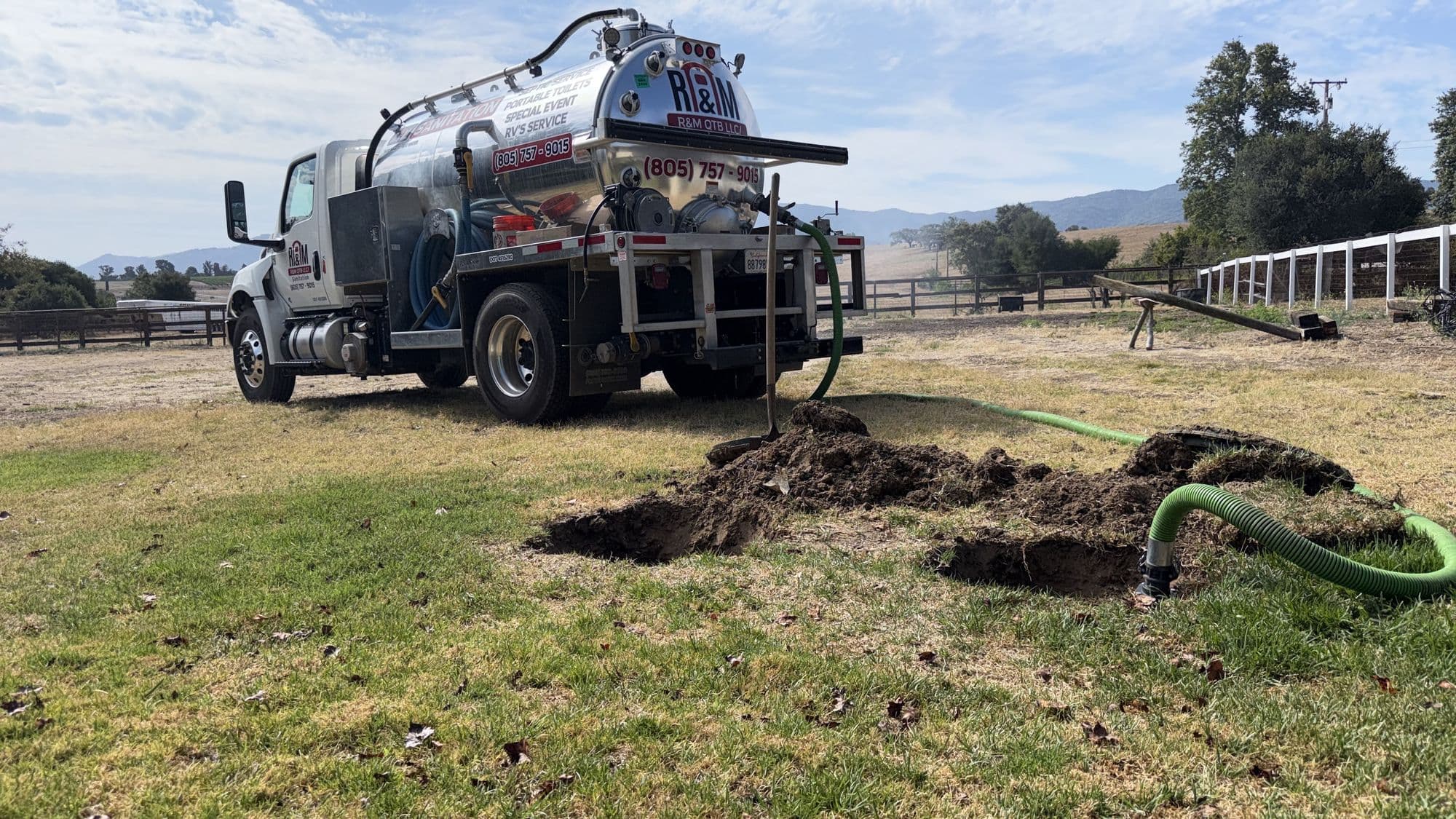 Septic tank lids dug out on a ranch while the R&M vacuum truck pumps the tank through a suction hose